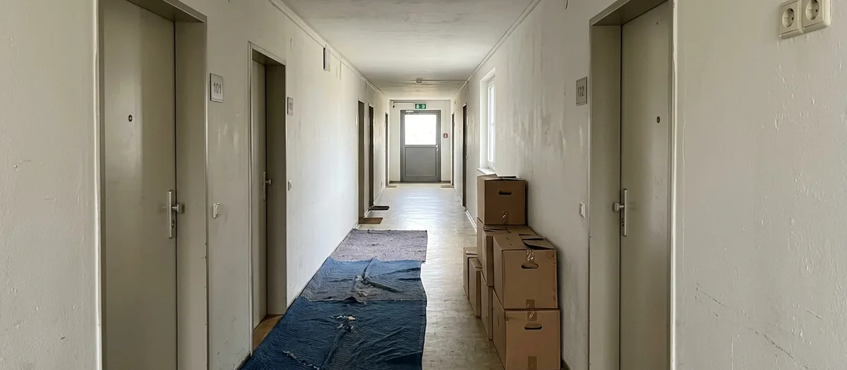 Langer Flur im Plattenbau, eine Plane schützt den Boden, Kartons stehen an der Wand